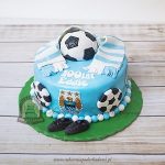 Tort z logo Manchester City ozdobiony piłkami, szalikiem kibica i korkami