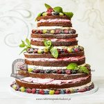 Piętrowy naked cake z ciemnym biszkoptem owocami sezonowymi i listkami mięty oprószony cukrem pudrem