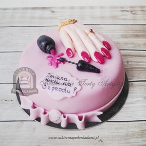 Różowy tort z dłonią z wypielęgnowanymi paznokciami i lakierem do paznokci